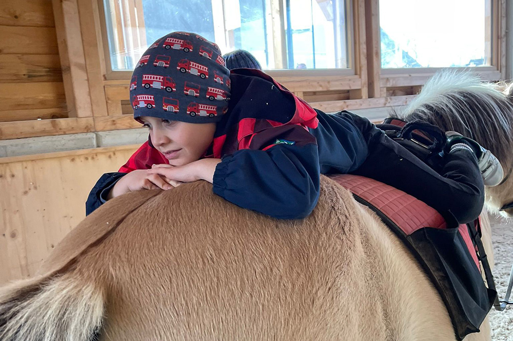 Kind entspannt liegend auf Pferderücken